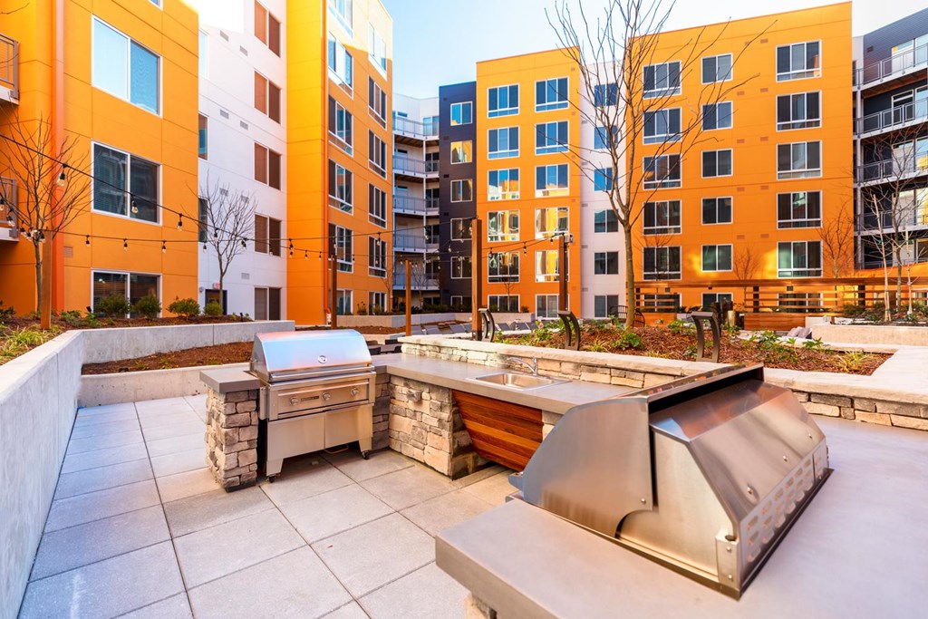 A modern outdoor kitchen area with a grill and sink.