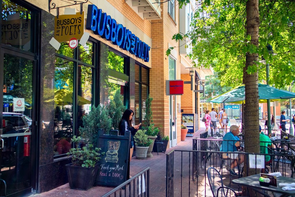A woman is standing outside a restaurant named Busboys and Poets.