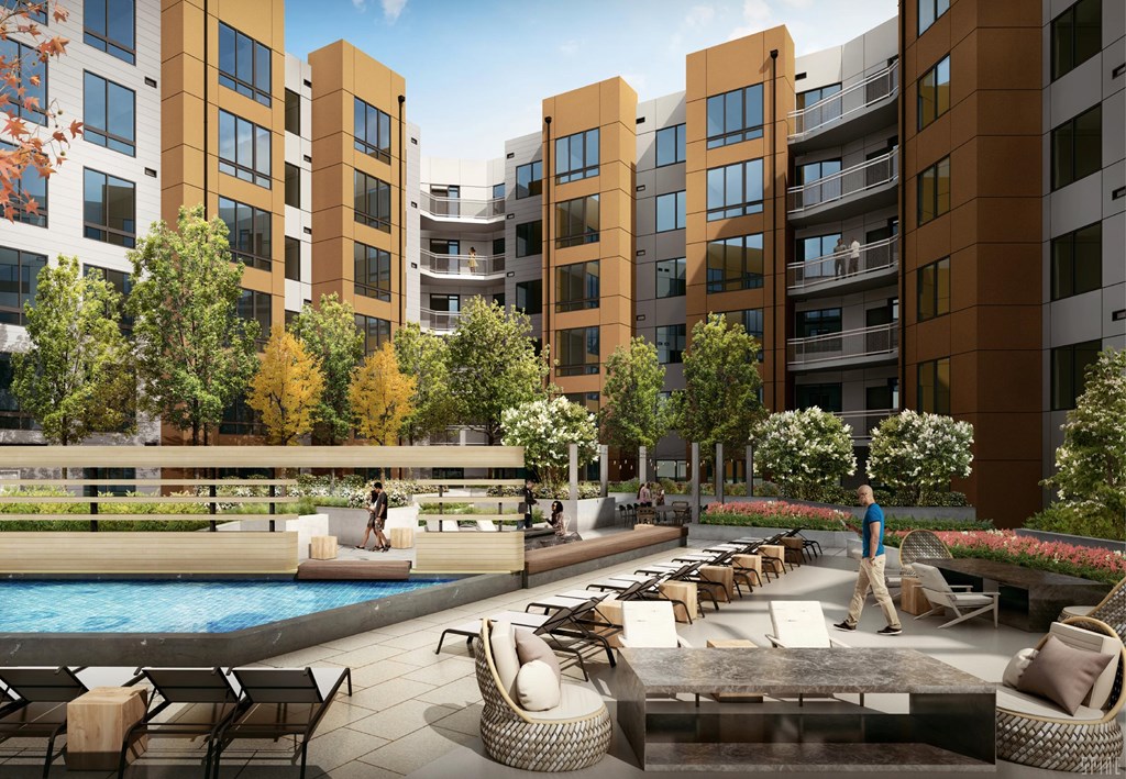 A man is walking in a courtyard with a pool and chairs.