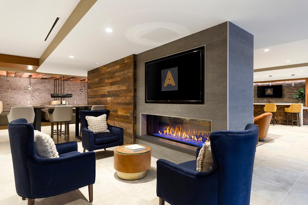 A modern living room with a fireplace and blue chairs.