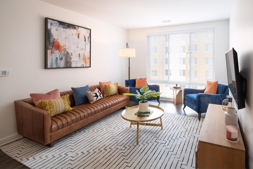 A living room with a brown couch, a coffee table, and a painting on the wall.