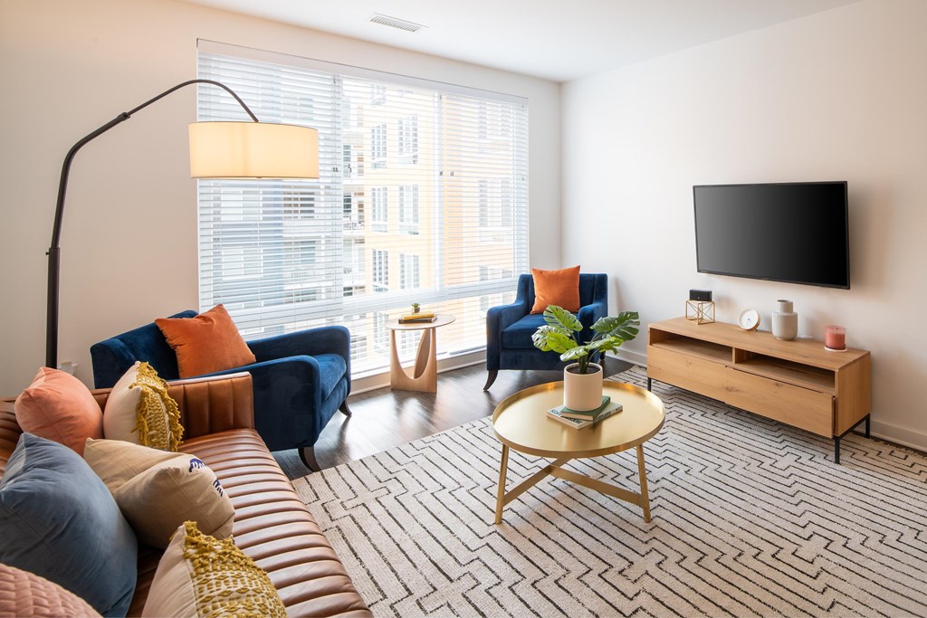 A living room with a blue couch, a yellow coffee table, and a flat screen TV mounted on the wall.