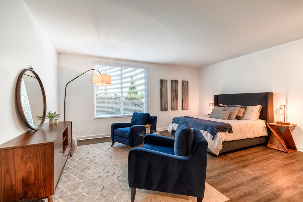 A bedroom with a bed, chair, and lamp.