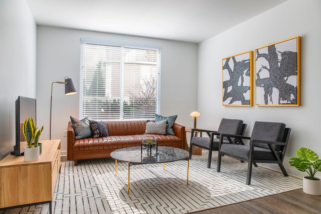 A living room with a brown couch, a coffee table, and two chairs.