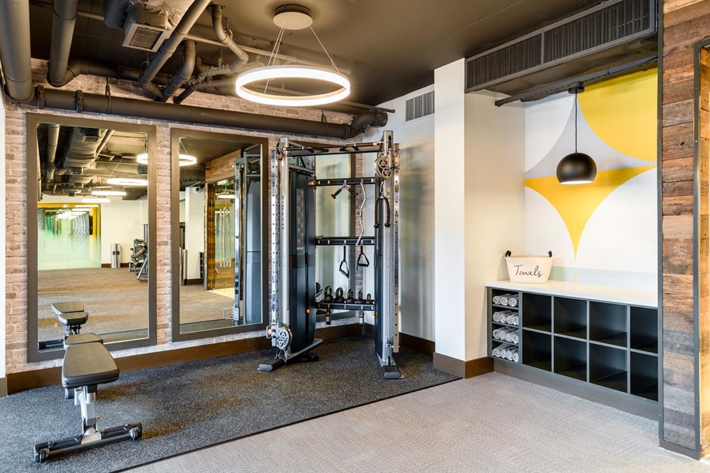 A gym with a variety of equipment including a treadmill, weights, and a bench.
