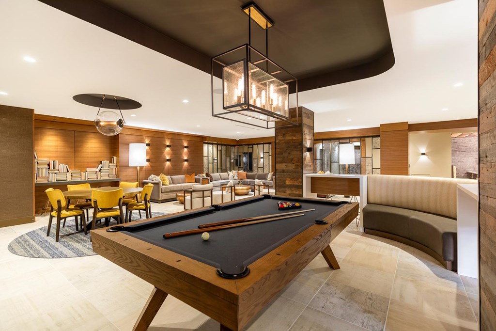 A pool table is in the middle of a room with a couch and chairs.