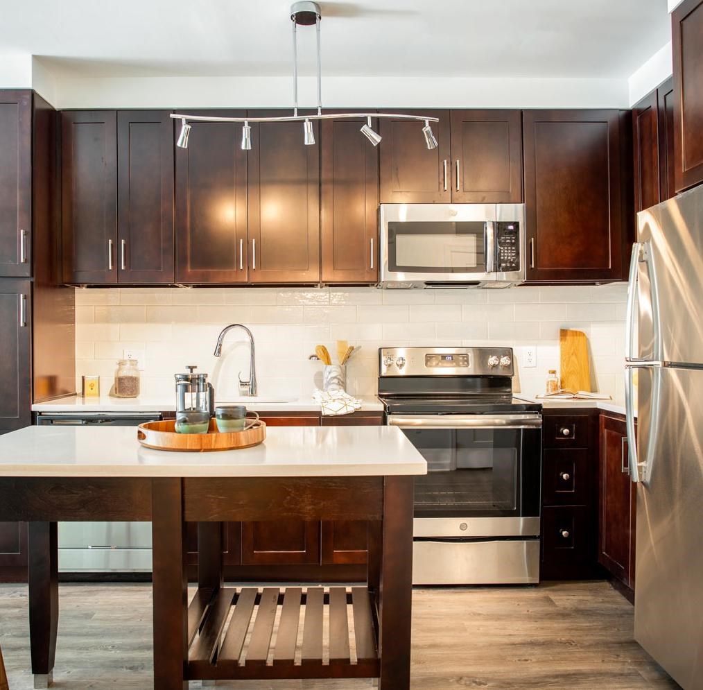 A kitchen with a wooden table and stainless steel appliances.