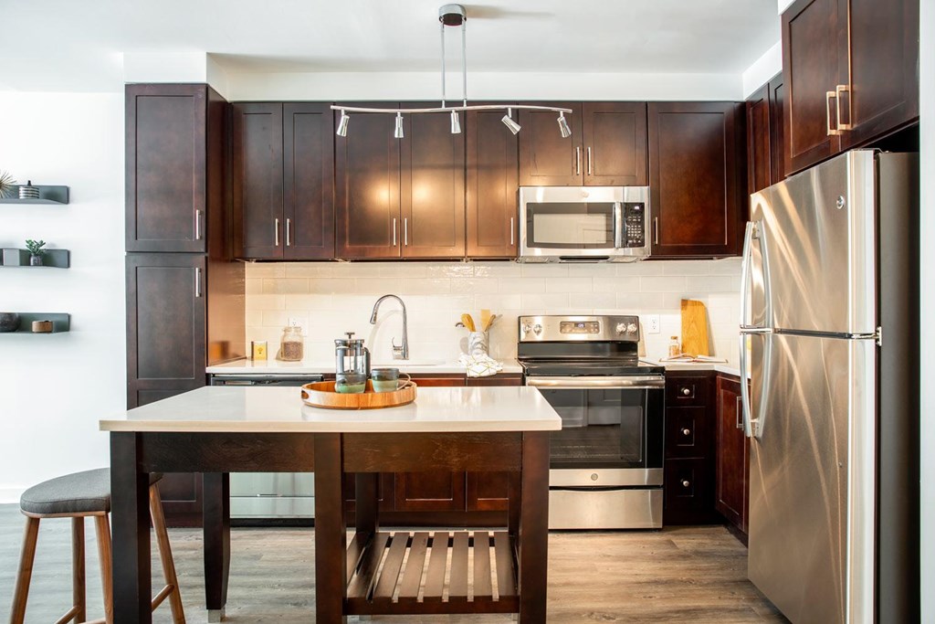 A modern kitchen with a wooden table and stainless steel appliances.