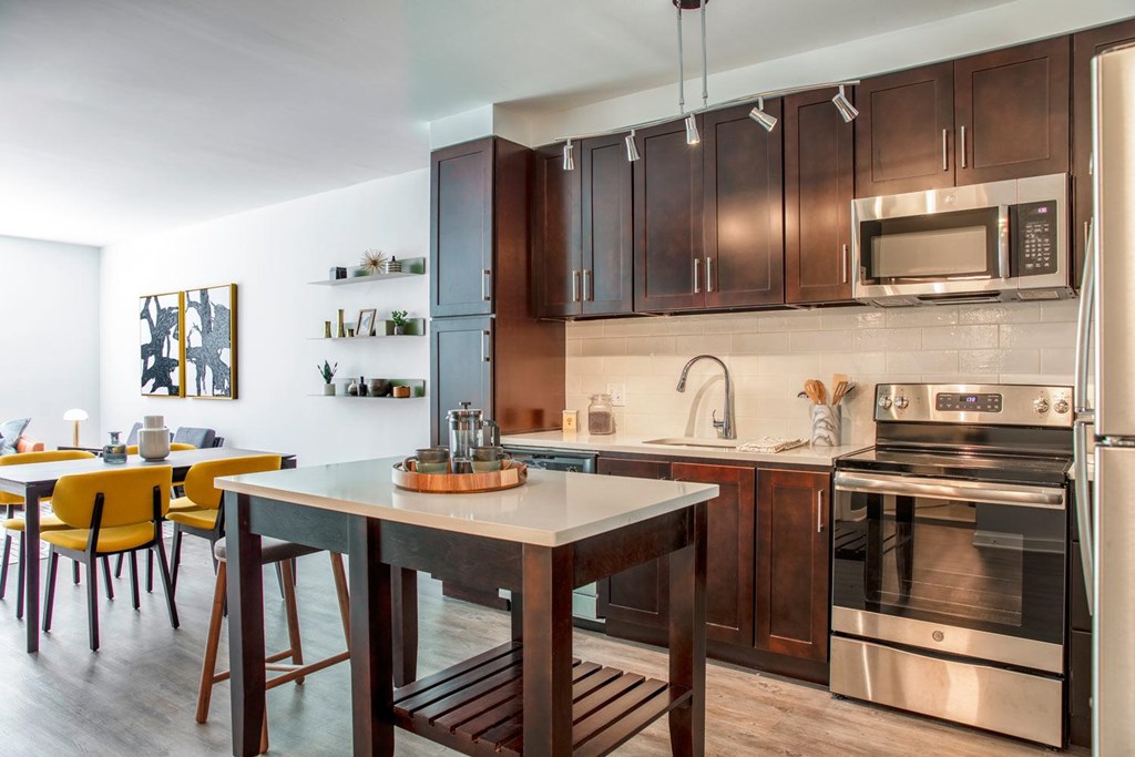 A modern kitchen with dark wood cabinets and stainless steel appliances.