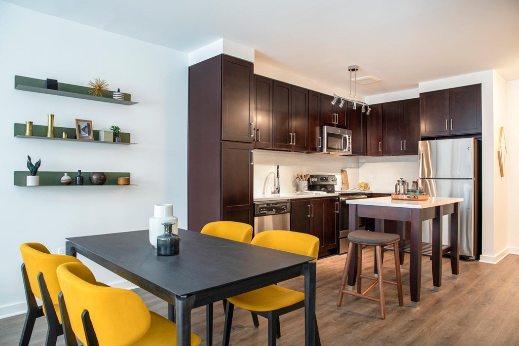 A modern kitchen with a dining table and yellow chairs.
