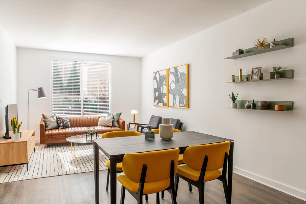 A modern dining room with a black table and yellow chairs.