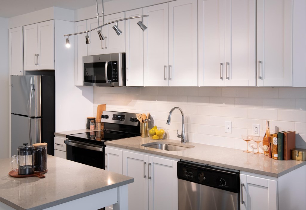 A modern kitchen with white cabinets and black appliances.