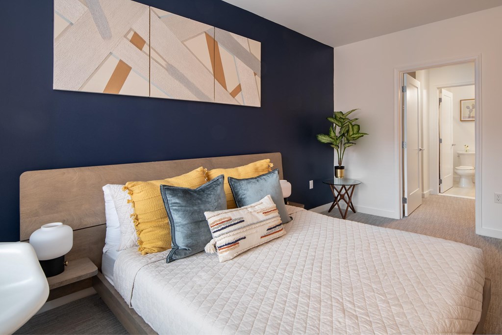 A bedroom with a bed, pillows, and a lamp.