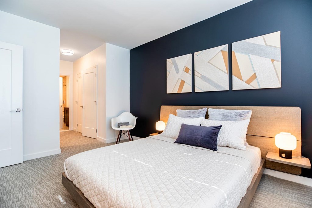 A bedroom with a large bed and a white chair.