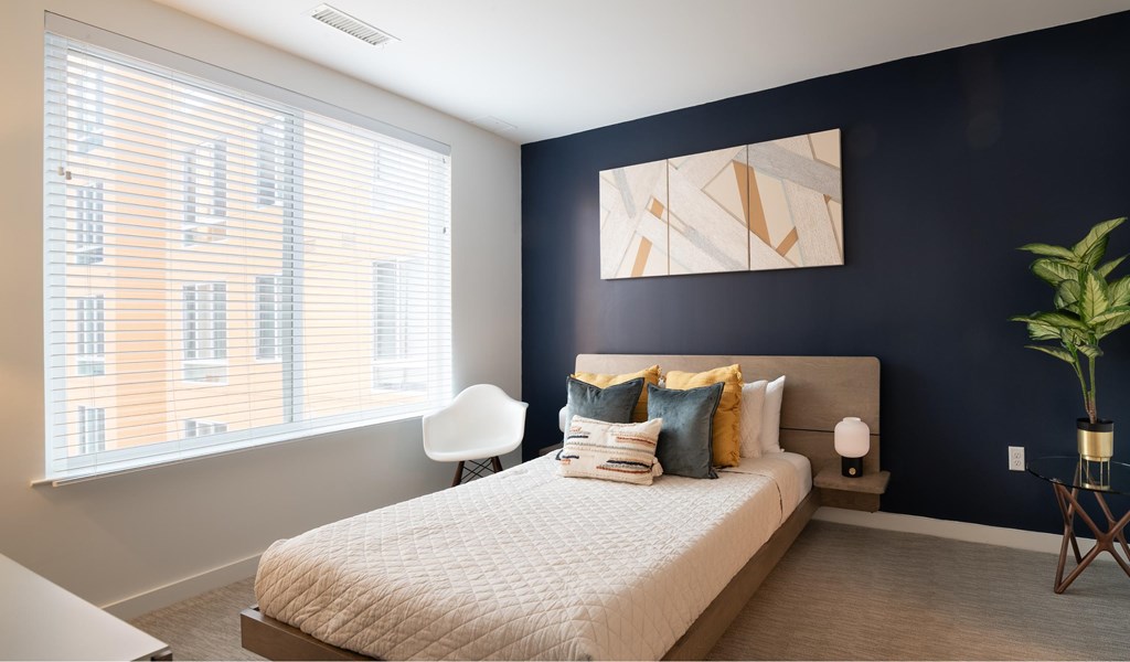 A bedroom with a large bed and a window with blinds.