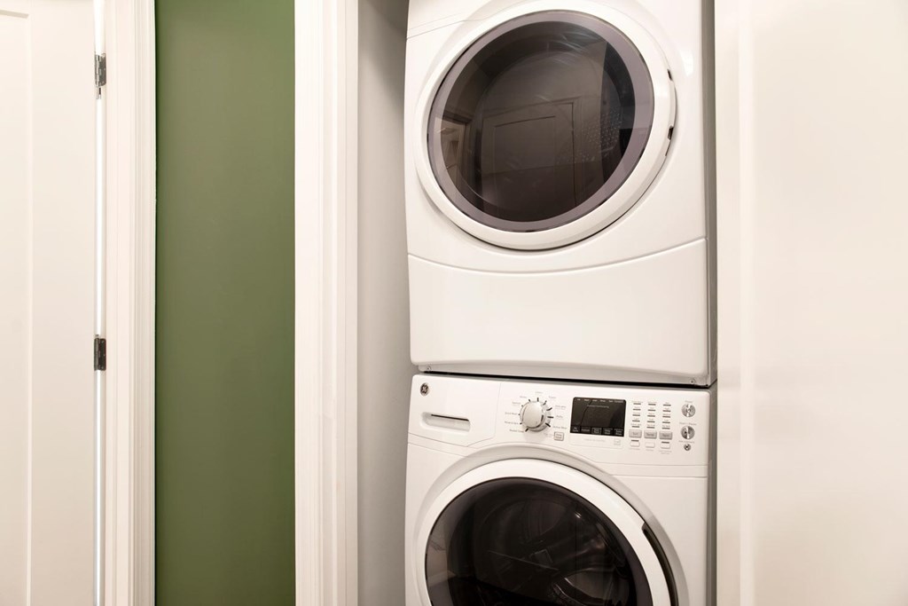 A white washing machine is stacked on top of another white washing machine.