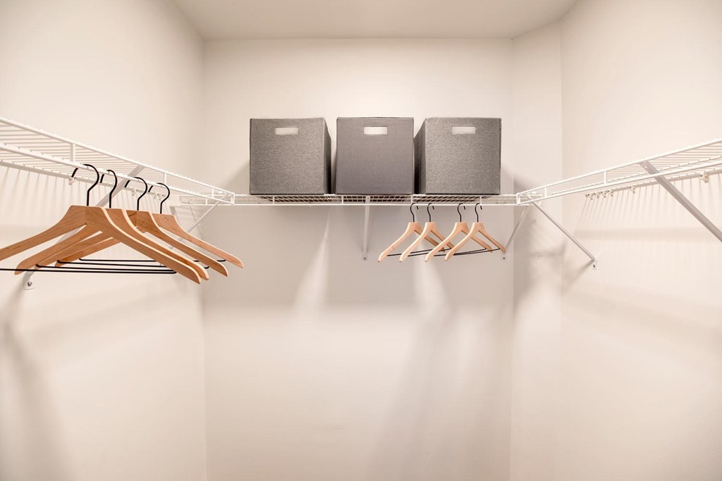 Three black speakers on a shelf with wooden hangers.