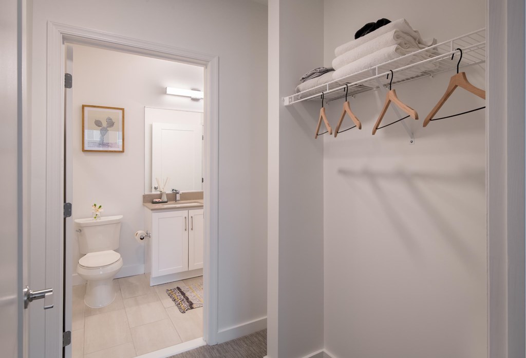 A bathroom with a toilet, sink, and a white wall.