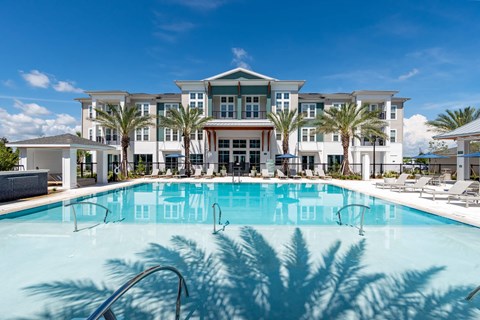 The pool area at Corban Freedom Apartments in Orlando, FL, featuring lounge chairs, a shade structure, and palm trees.
