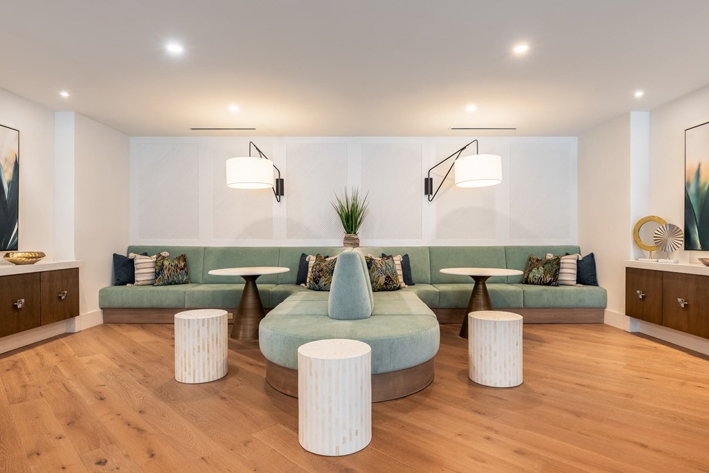 A living room with a green couch and white ottomans.