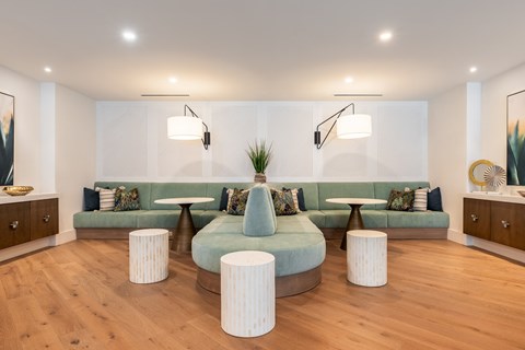A living room with a green couch and white ottomans.