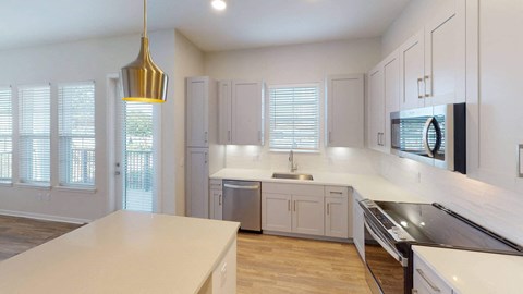A modern kitchen with a large island and stainless steel appliances.at Corban Freedom Apartments, Florida
