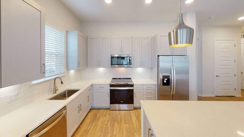 A modern kitchen with white cabinets and a wooden floor.at Corban Freedom Apartments, Florida, 32837