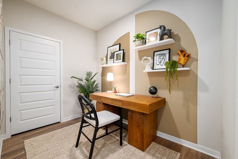 Model office at Corban Freedom Apartments in Orlando, FL, featuring wood grain floor paneling and a desk.