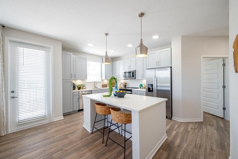 A kitchen with a white island and wooden floors.at Corban Freedom Apartments, Florida