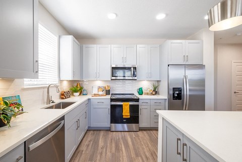 A modern kitchen with white cabinets and stainless steel appliances.at Corban Freedom Apartments, Orlando, 32837
