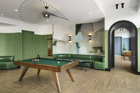 A pool table is in the middle of a room with green walls.