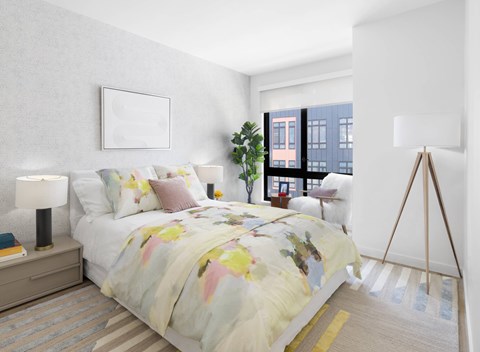 A bedroom with a bed, a lamp, a plant, and a picture on the wall.