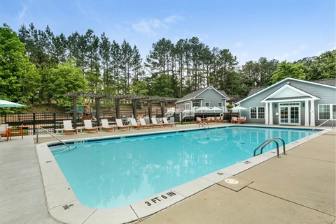 Pool next to line of tall trees at Aqua Sandy Springs apartments for rent in Sandy Springs, GA.