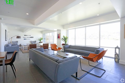 A living room with a grey couch and orange chairs.
