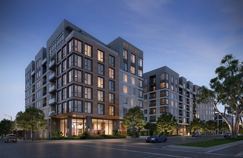 A modern apartment building named "REVEN" is shown at dusk with lights on inside the building.