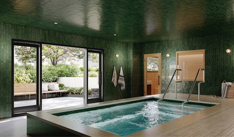 A small indoor pool with a wooden deck and a glass wall.