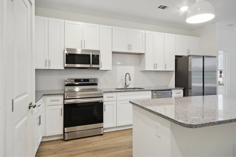 A kitchen with white cabinets and stainless steel appliances.