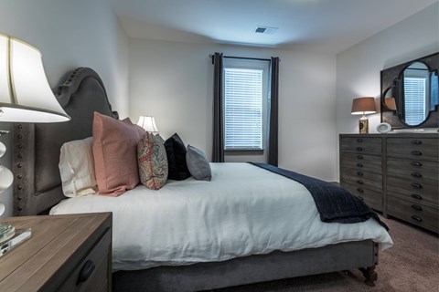 A bedroom with a bed, nightstand, and a lamp.