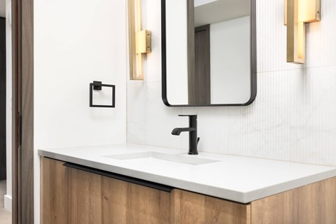 A modern bathroom with a white sink and a rectangular mirror.