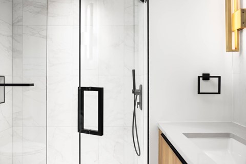 A bathroom with a white sink and a glass shower door.