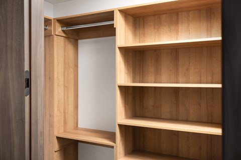 A wooden shelving unit with four shelves is open to reveal a white interior.