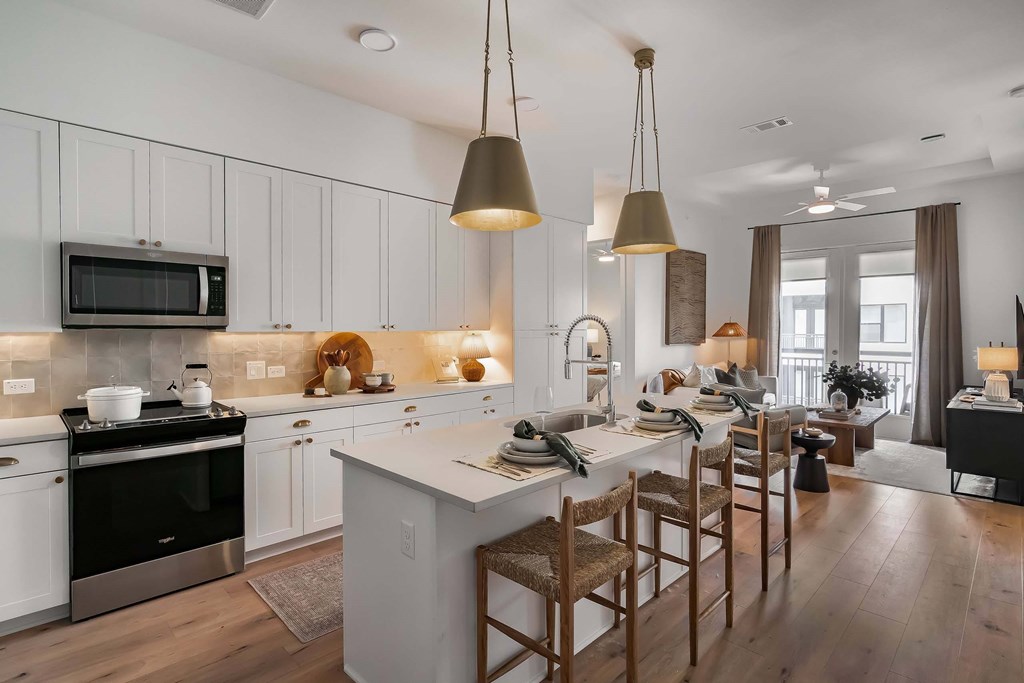 A modern kitchen with a large island and wooden chairs.
