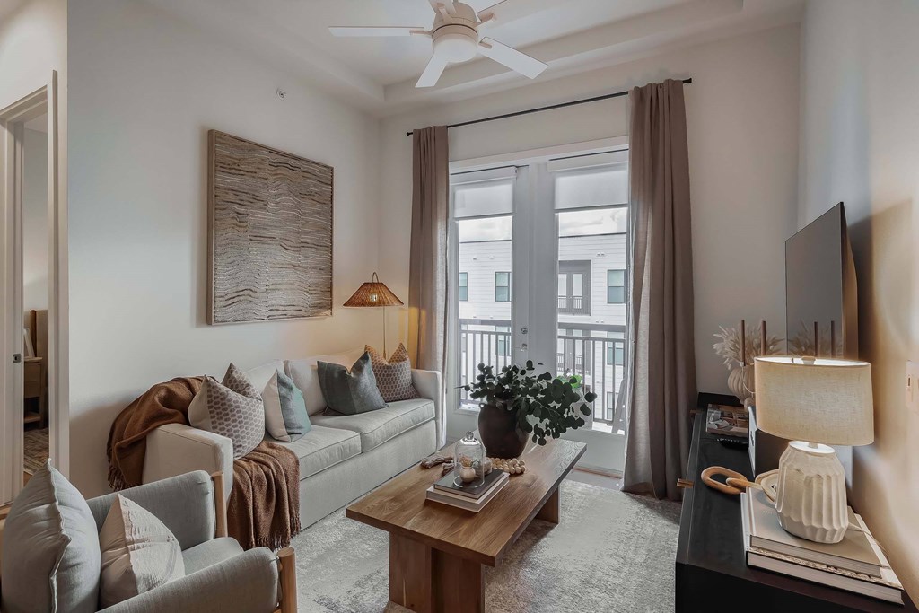 A living room with a couch, chairs, a coffee table, and a flat screen TV.