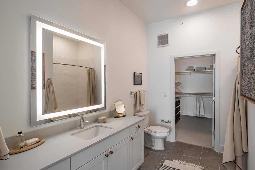 A bathroom with a white toilet, sink, and mirror.