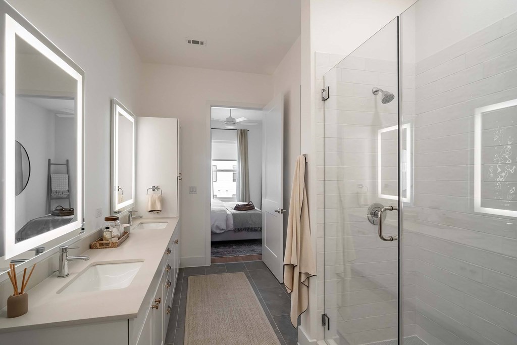 A bathroom with a walk-in shower and double sinks.