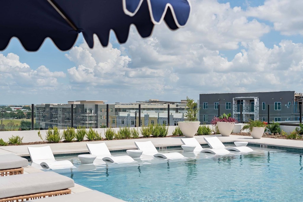 A pool with white chairs and a building in the background.