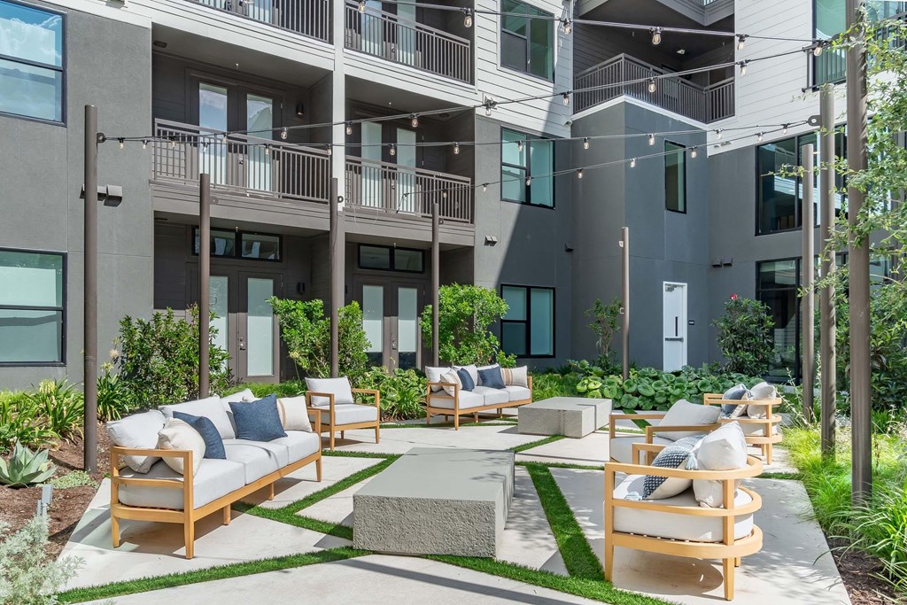 A modern outdoor seating area with wooden furniture and a green lawn.