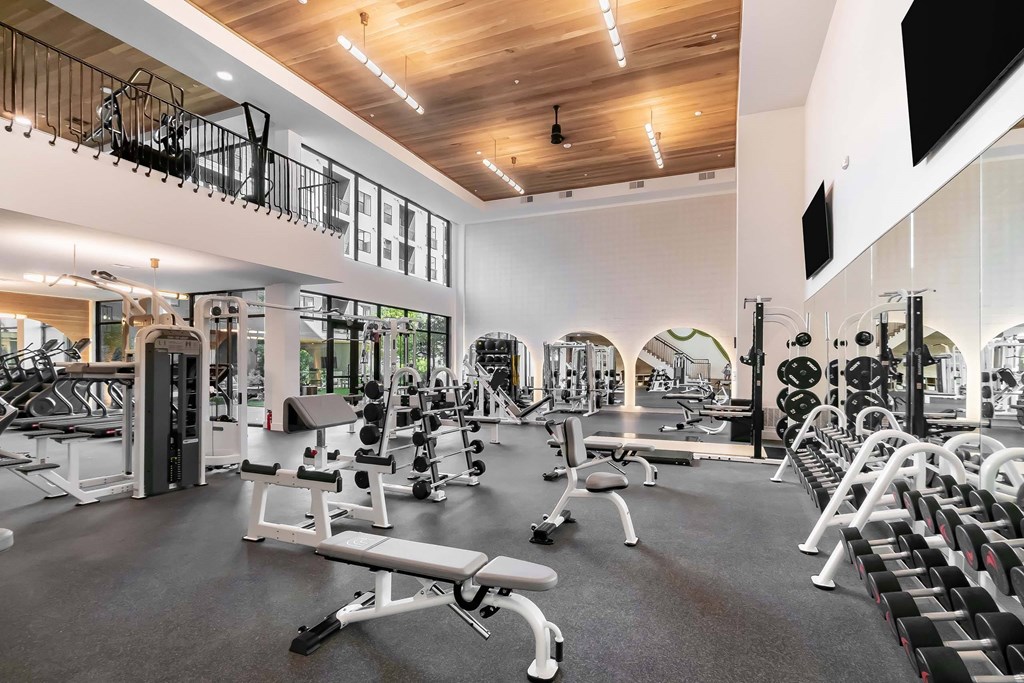 A spacious gym with a variety of equipment and a balcony area.