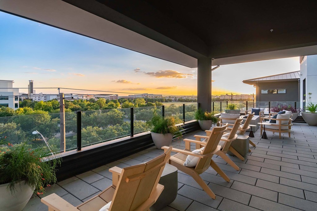 A patio with wooden chairs and a view of the city.