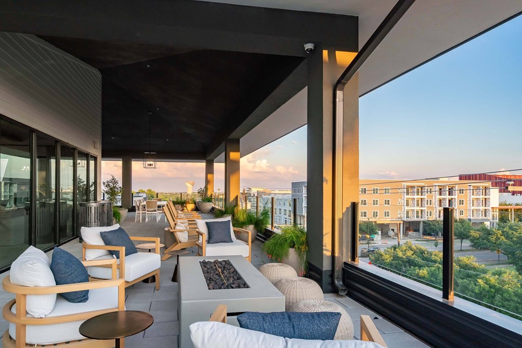A patio with white furniture and a view of the city.
